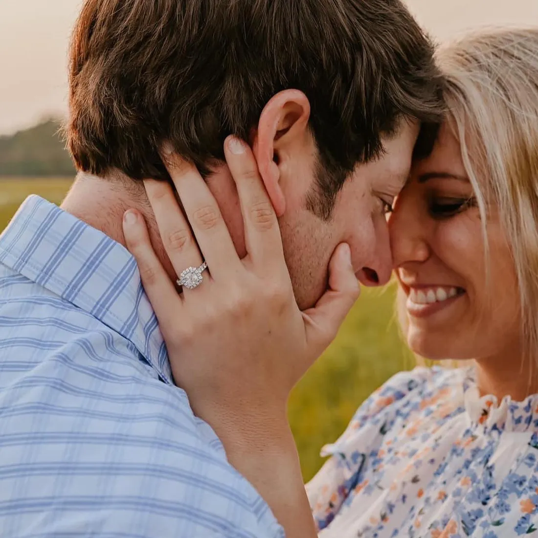 A couple lovingly embraces, showcasing an engagement ring.