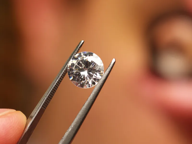A diamond held by tweezers, showcasing its clarity and brilliance.