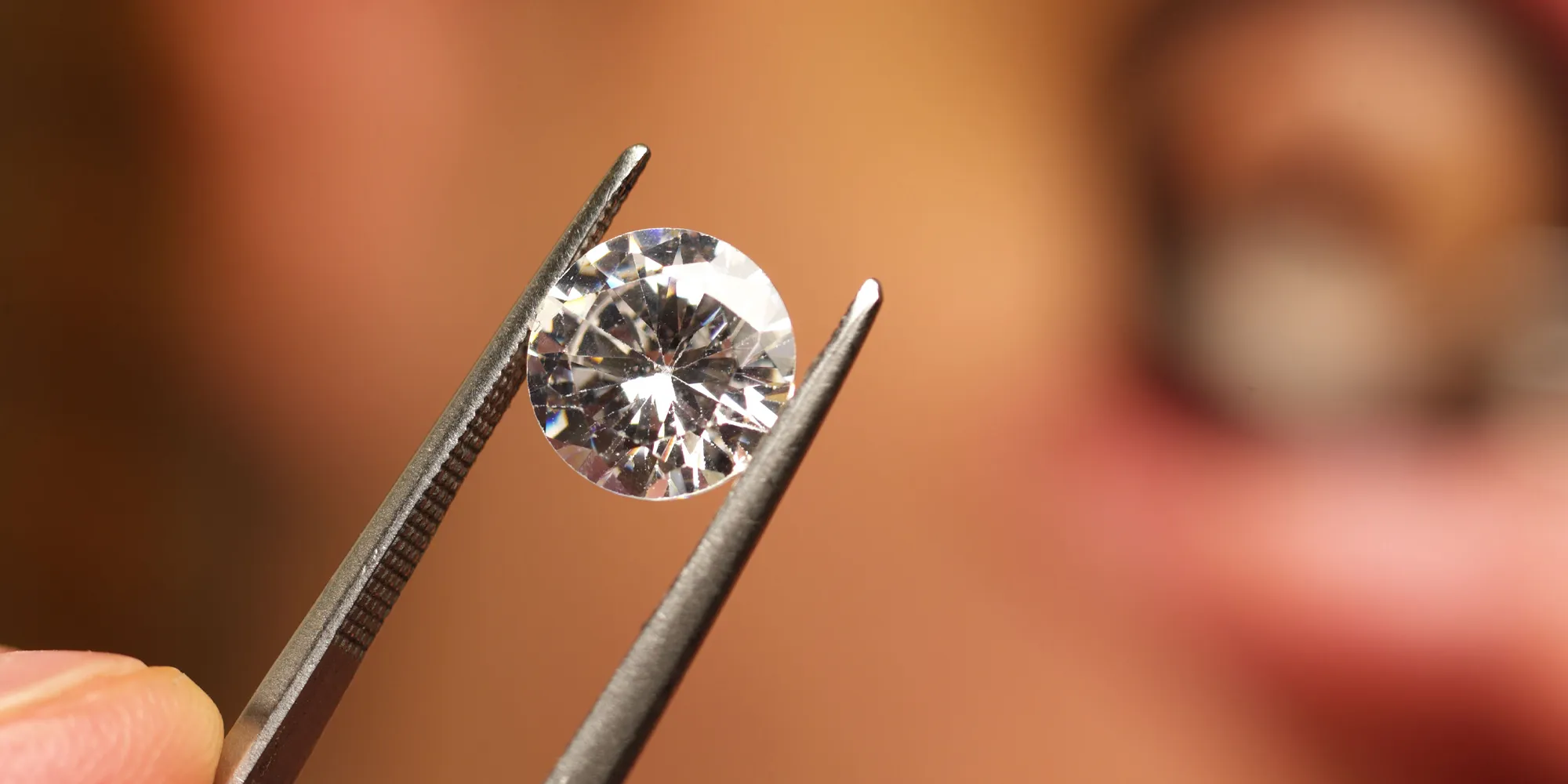 A diamond held by tweezers, showcasing its clarity and brilliance.
