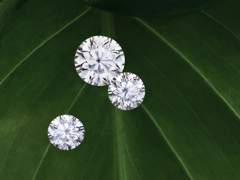 Three sparkling diamonds on a vibrant green leaf background.