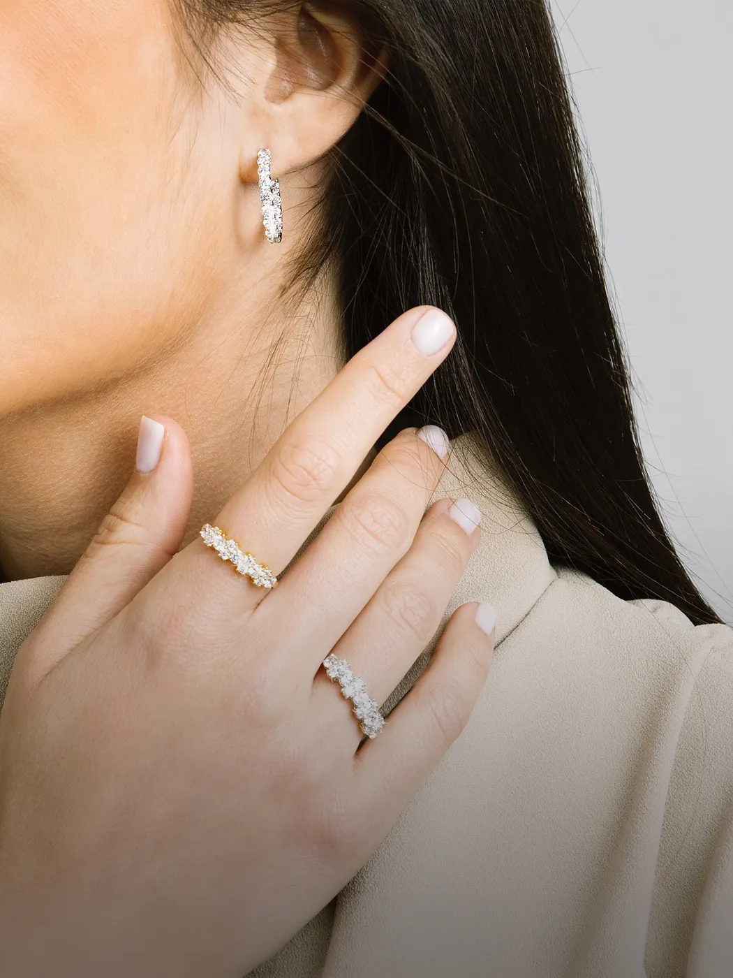 Woman wearing diamond hoop earring and two diamond rings on her hand.