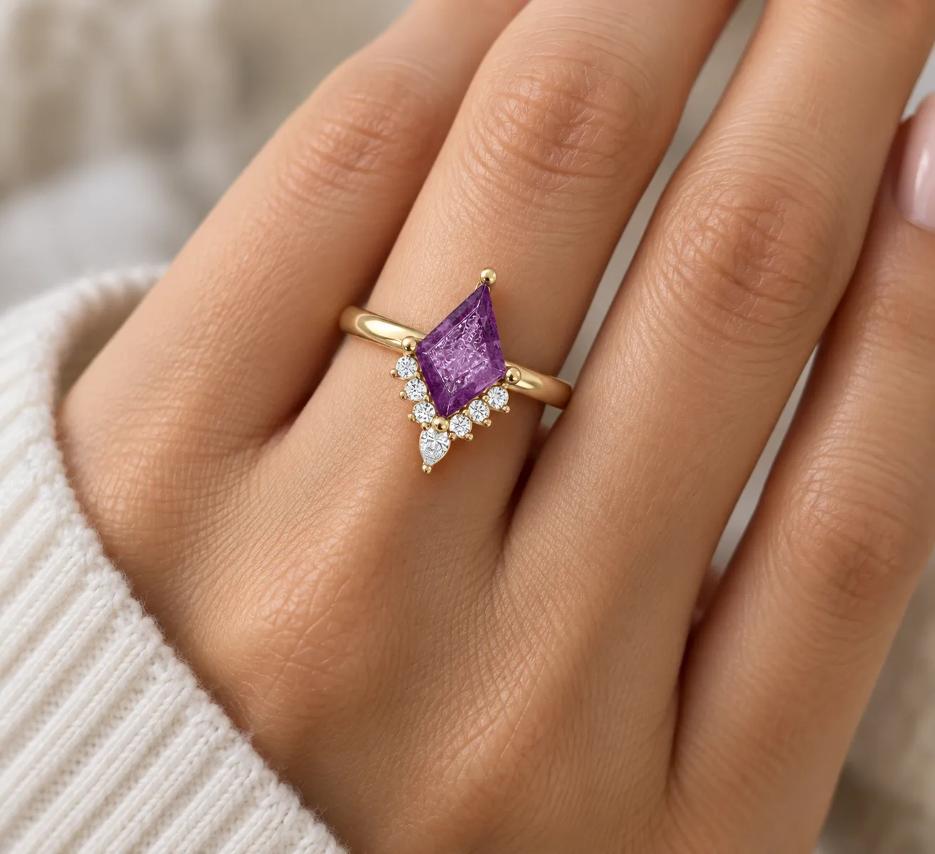 Hand wearing a custom yellow gold ring with a kite-cut amethyst, round diamonds and a pear-shaped diamond