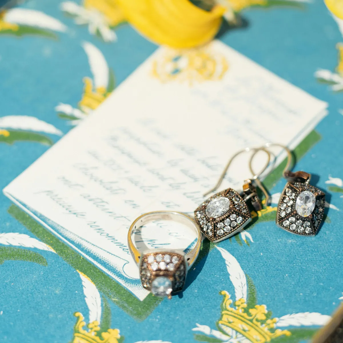 Elegant ring and earrings with gemstones on a decorative blue background.