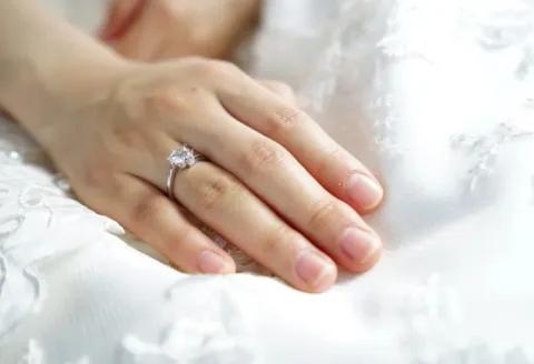 Hand wearing a custom engagement ring with diamond.
