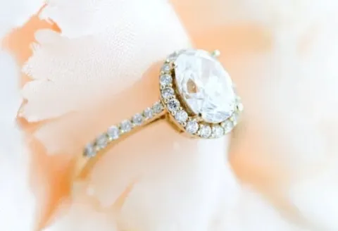 Gold halo diamond engagement ring on soft fabric.