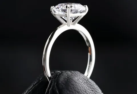 White gold solitaire engagement ring on black glove.