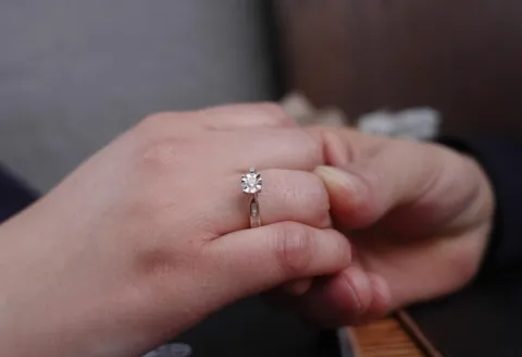Hand holding with a diamond engagement ring.