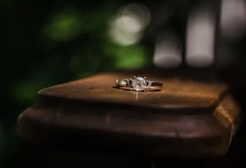Diamond engagement ring on wooden surface.