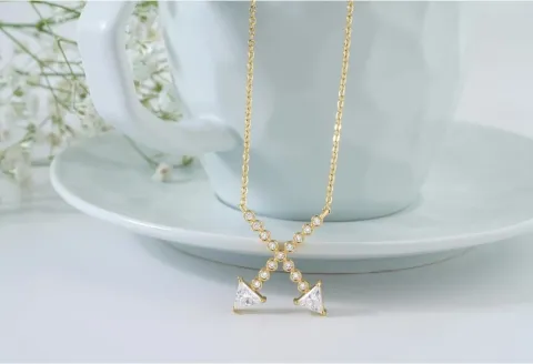Diamond-studded gold pendant beside a teacup