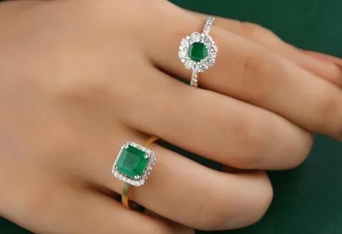 Hand wearing emerald engagement ring