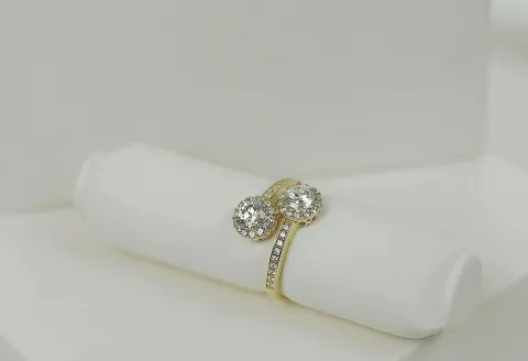 Gold gemstone engagement ring on a white cushion
