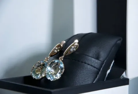 Gold drop earrings featuring oval-cut aquamarine gemstone