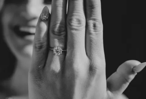 Woman showing off engagement ring, smiling.