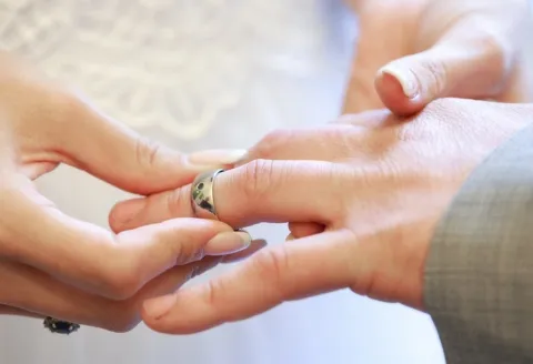 Close-up of hands exchanging men's wedding band