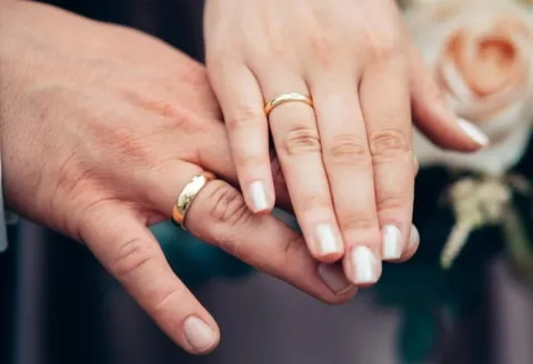 Couple showing off their gold wedding bands.