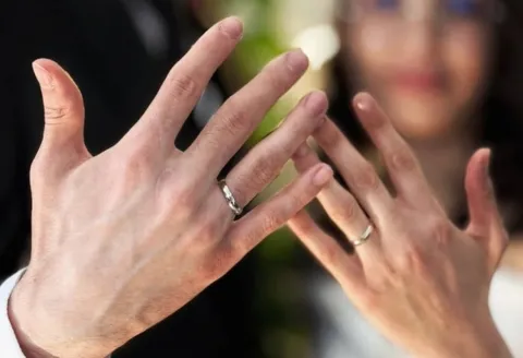 Close-up of hands with silver wedding bands.