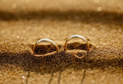 Two gold wedding band in the sand