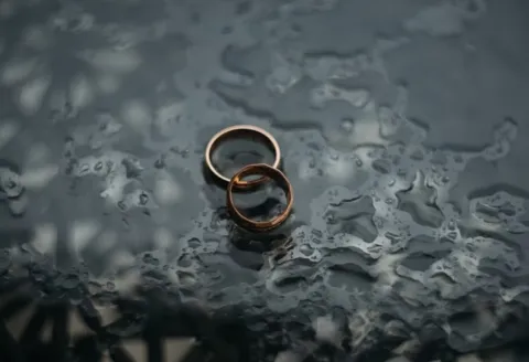 Rose gold men's wedding band on water