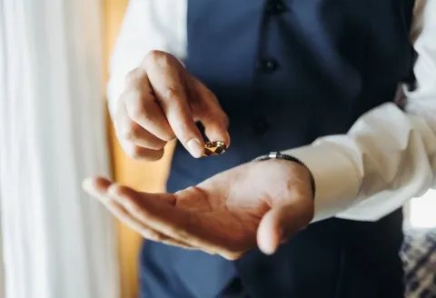 Groom holding men's wedding band carefully