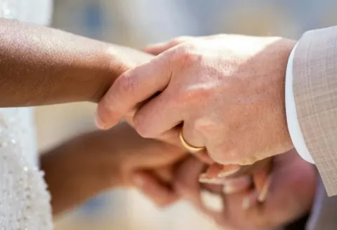 Groom placing gold men's wedding band
