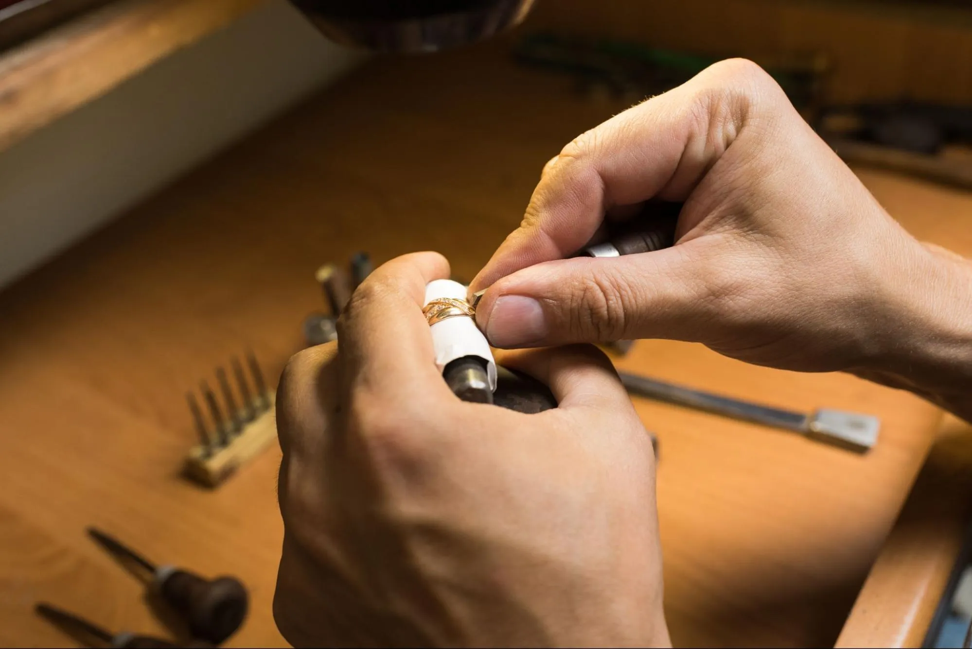 Final inspection of men's wedding band on jeweler's workbench