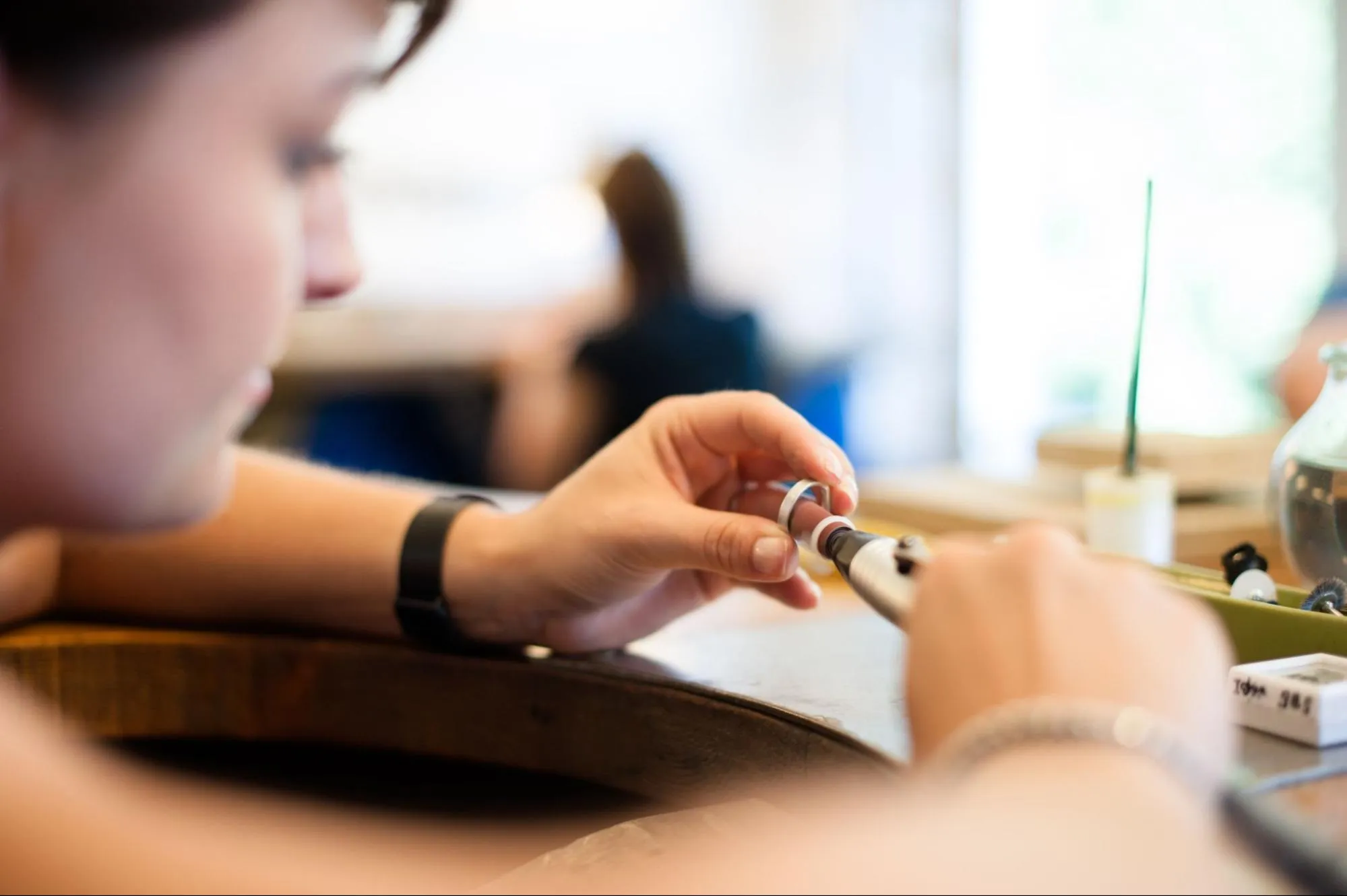 Jeweler polishing men's wedding band with rotary tool