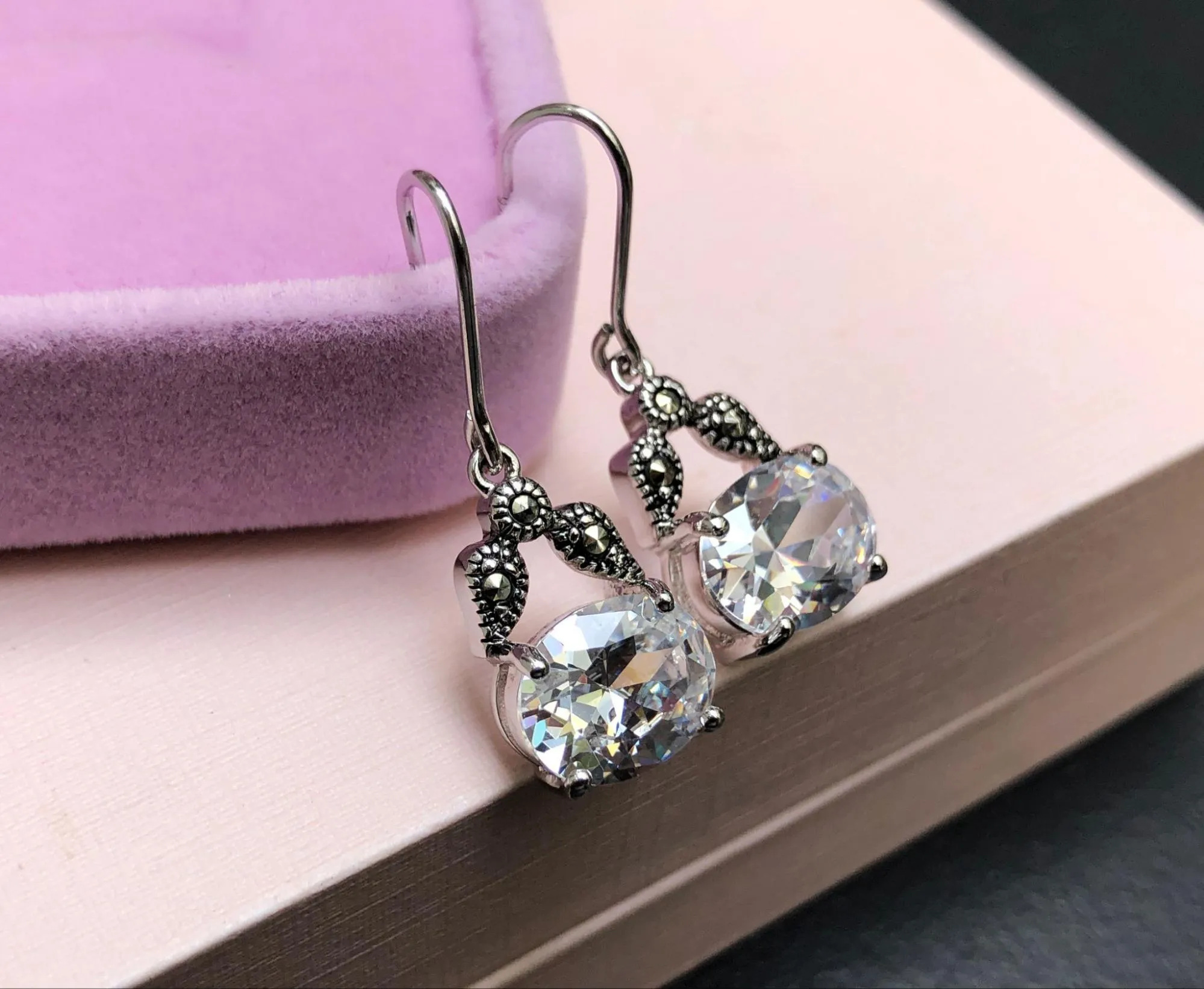 Diamond earrings placed beside pink jewelry box