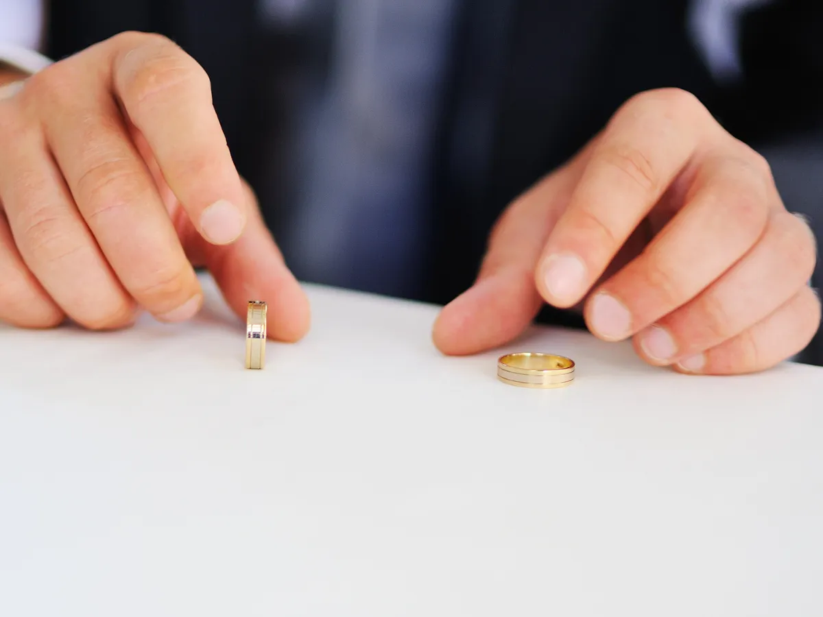 Close up of hands showing wedding bands on table