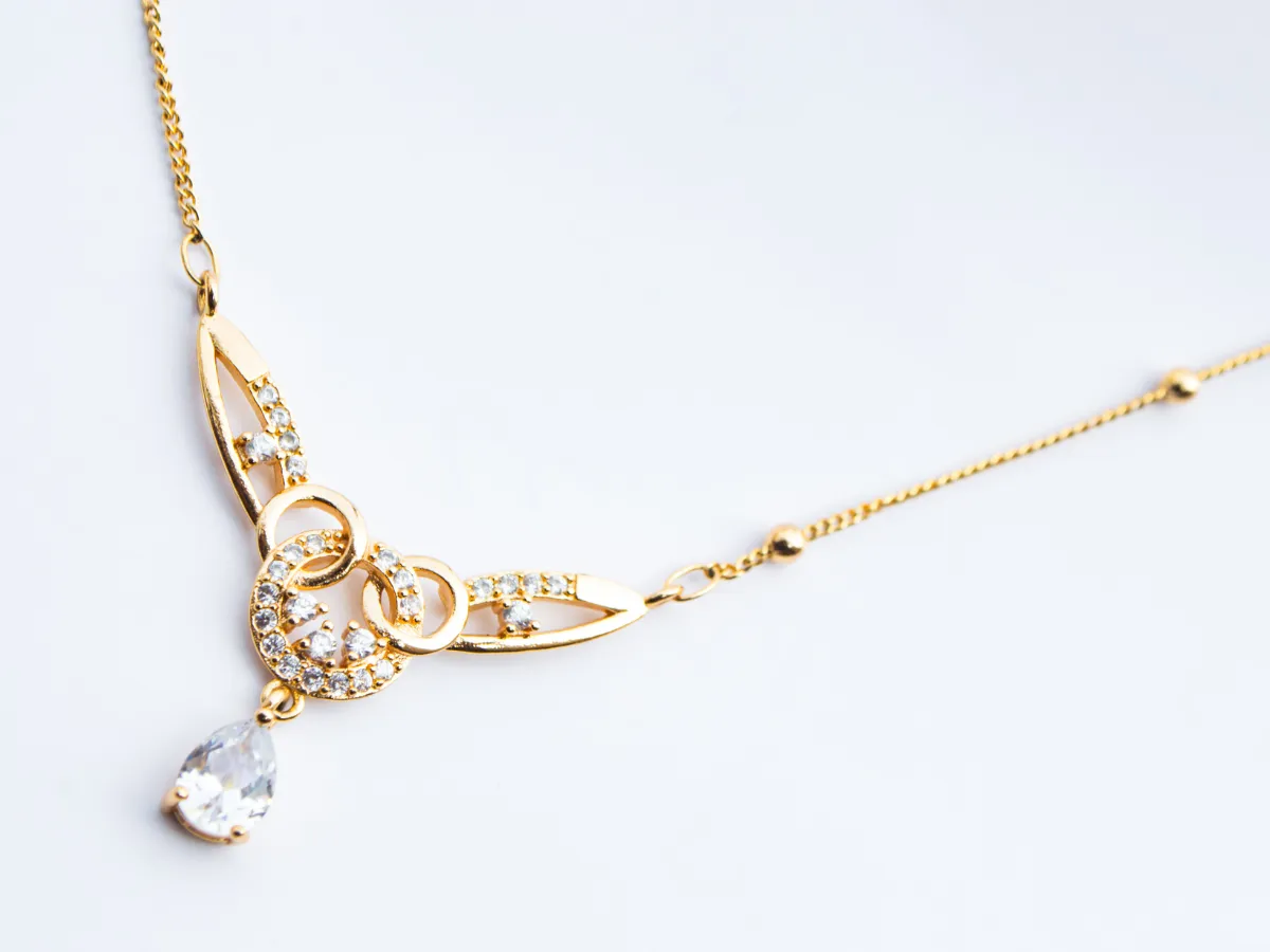 Yellow gold necklace with diamond pendant on white background