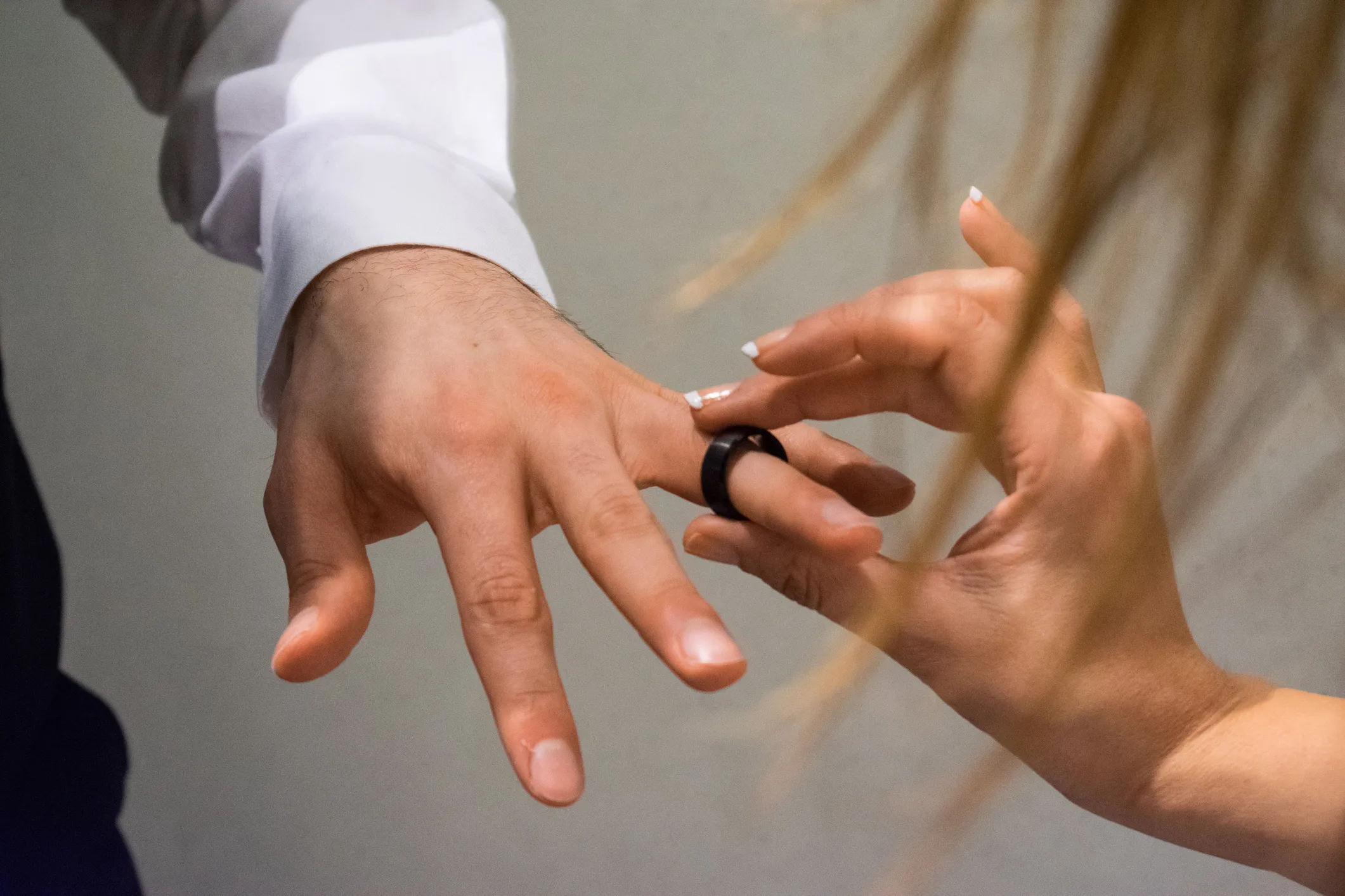 Bride placing men's wedding band on her groom.