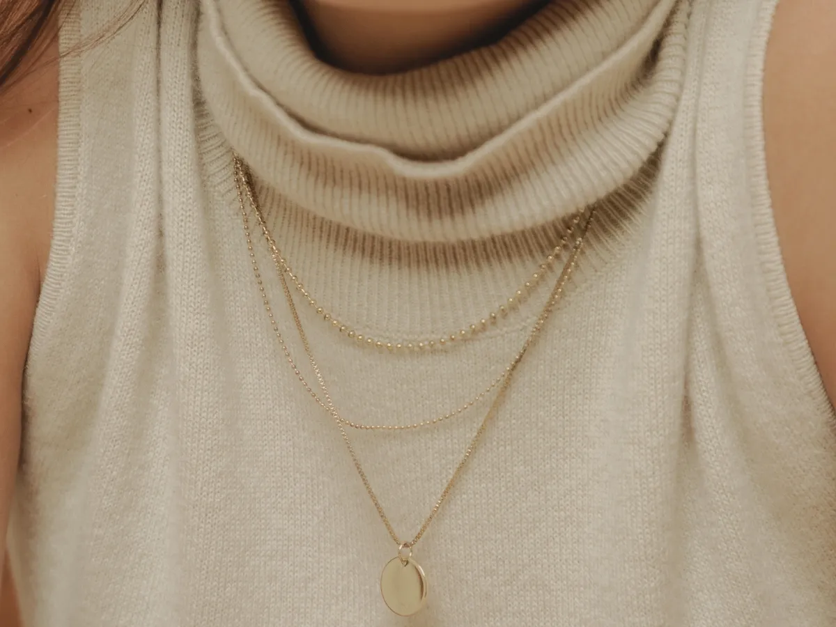 Layered gold necklaces on turtleneck