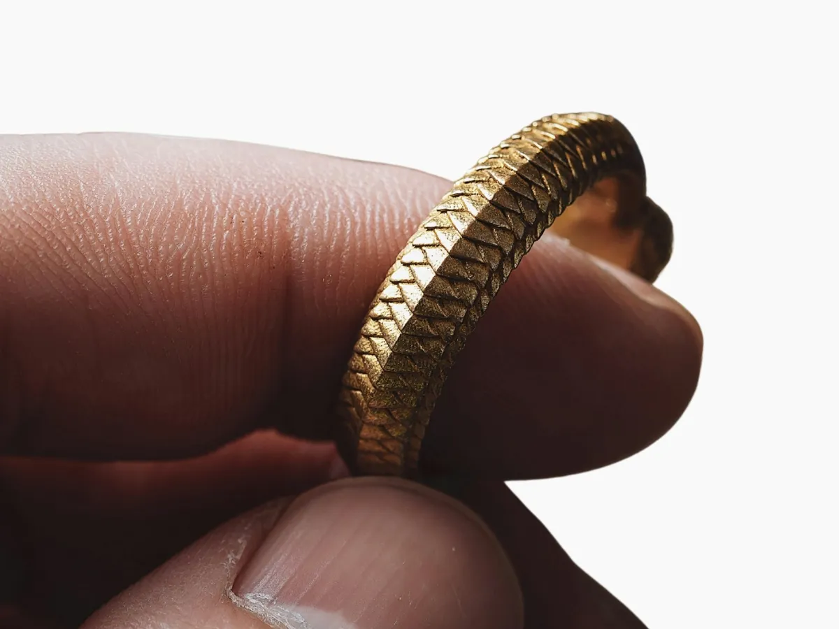 Gold ring with textured pattern held