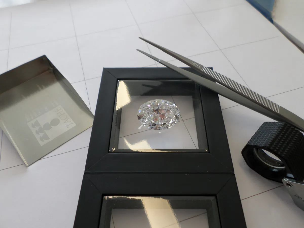 A loose diamond being evaluated with tweezers in a diamond grading tray
