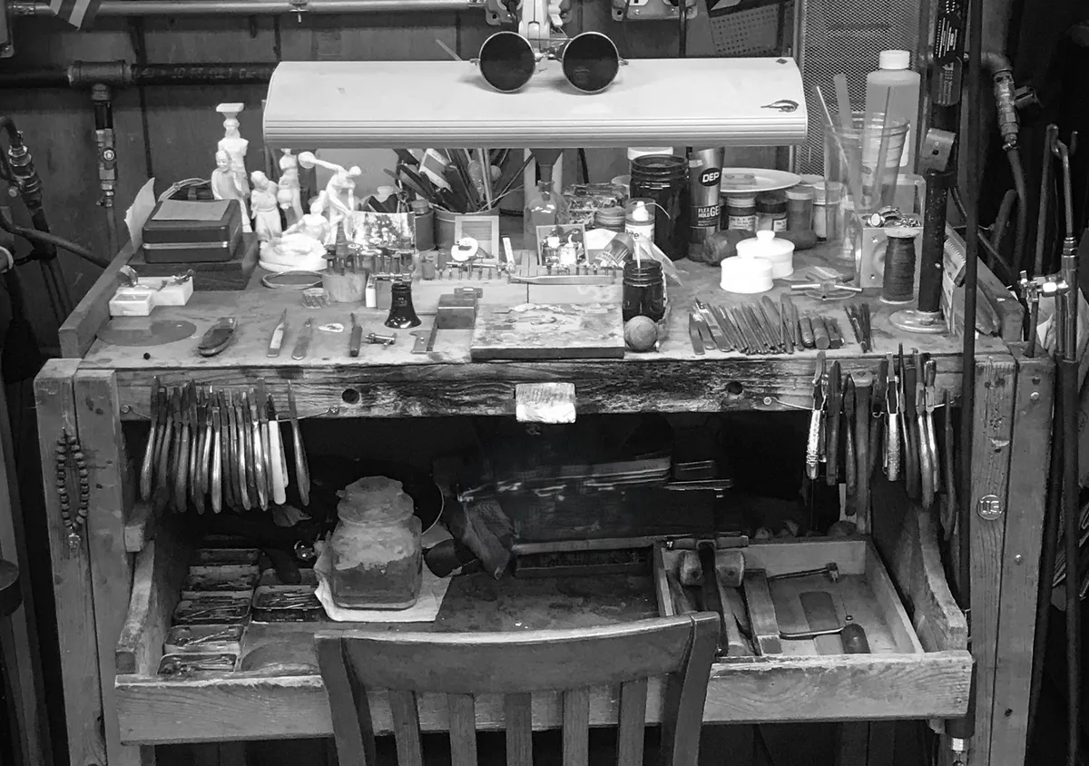 A well-worn jeweler's bench with hand tools, black and white