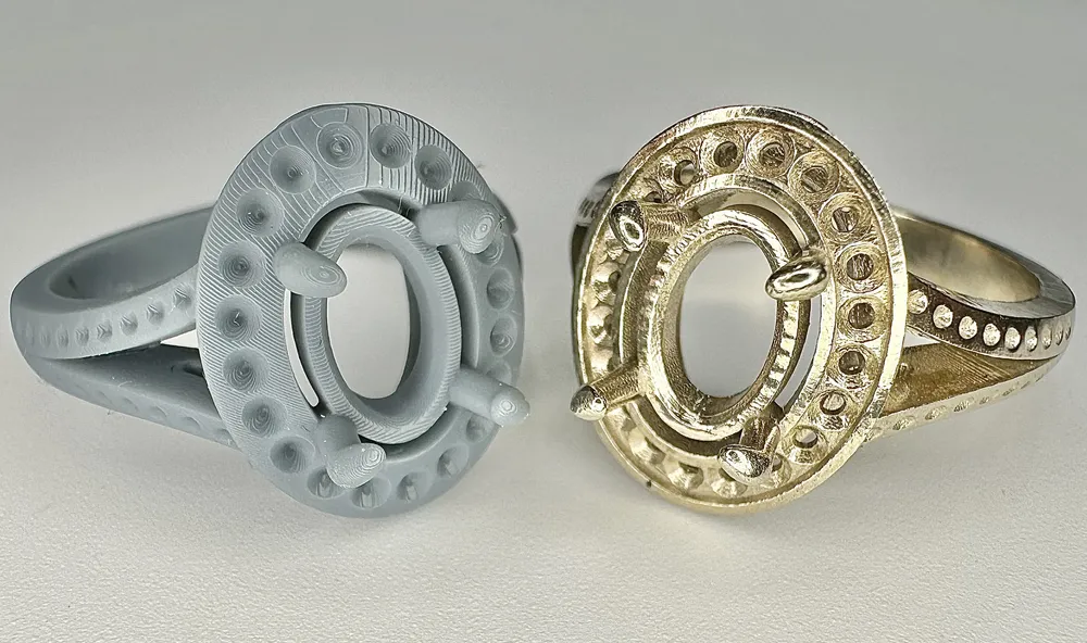 A carved wax ring model beside its finished gold casting