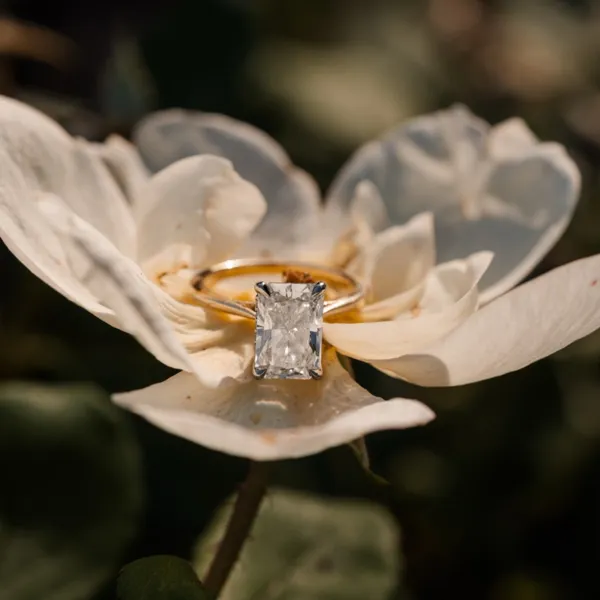 Custom yellow gold engagement ring with a rectangular diamond resting in a flower