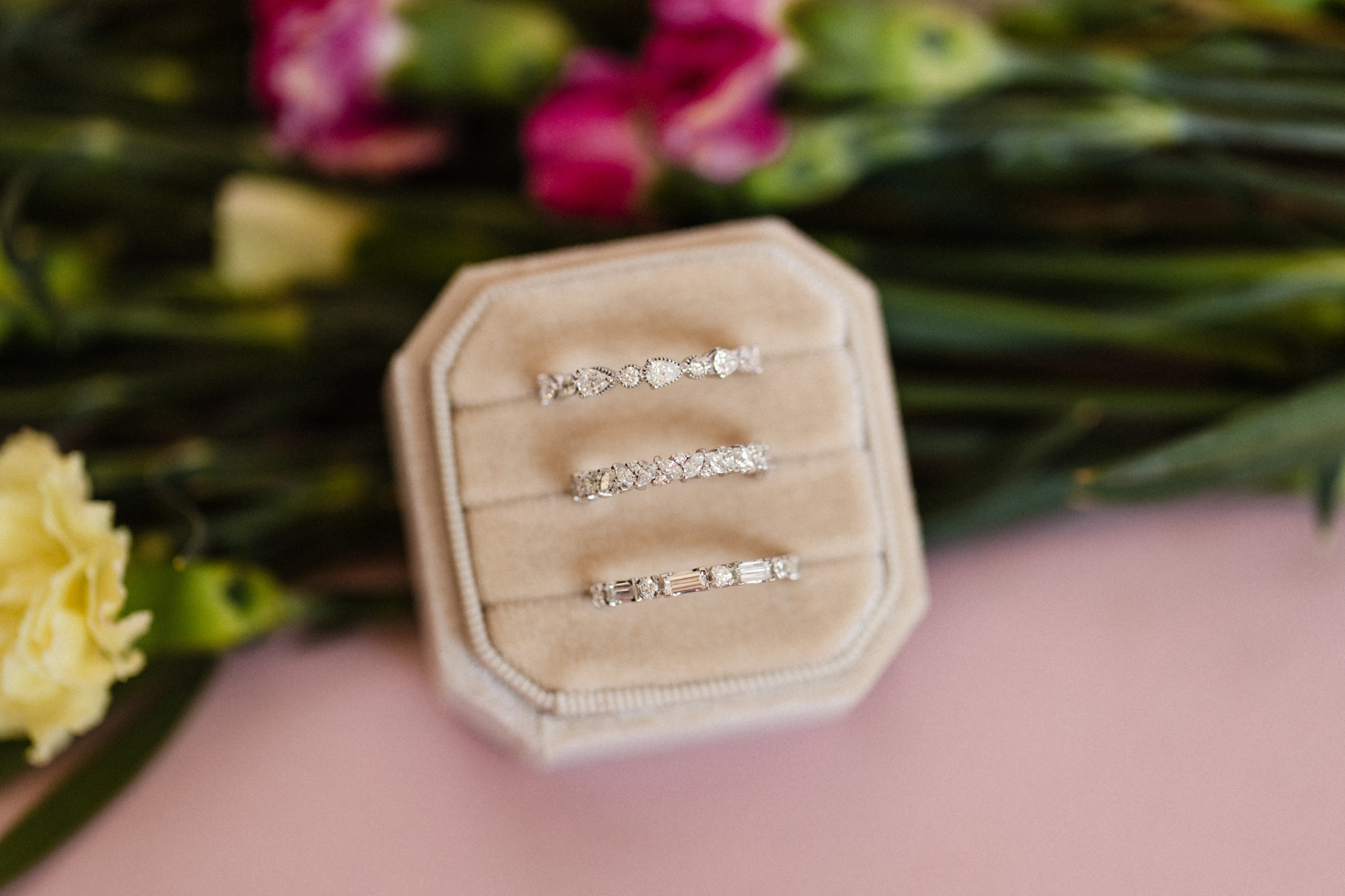 Three diamond wedding bands in a beige box with flowers. Click to view wedding bands.