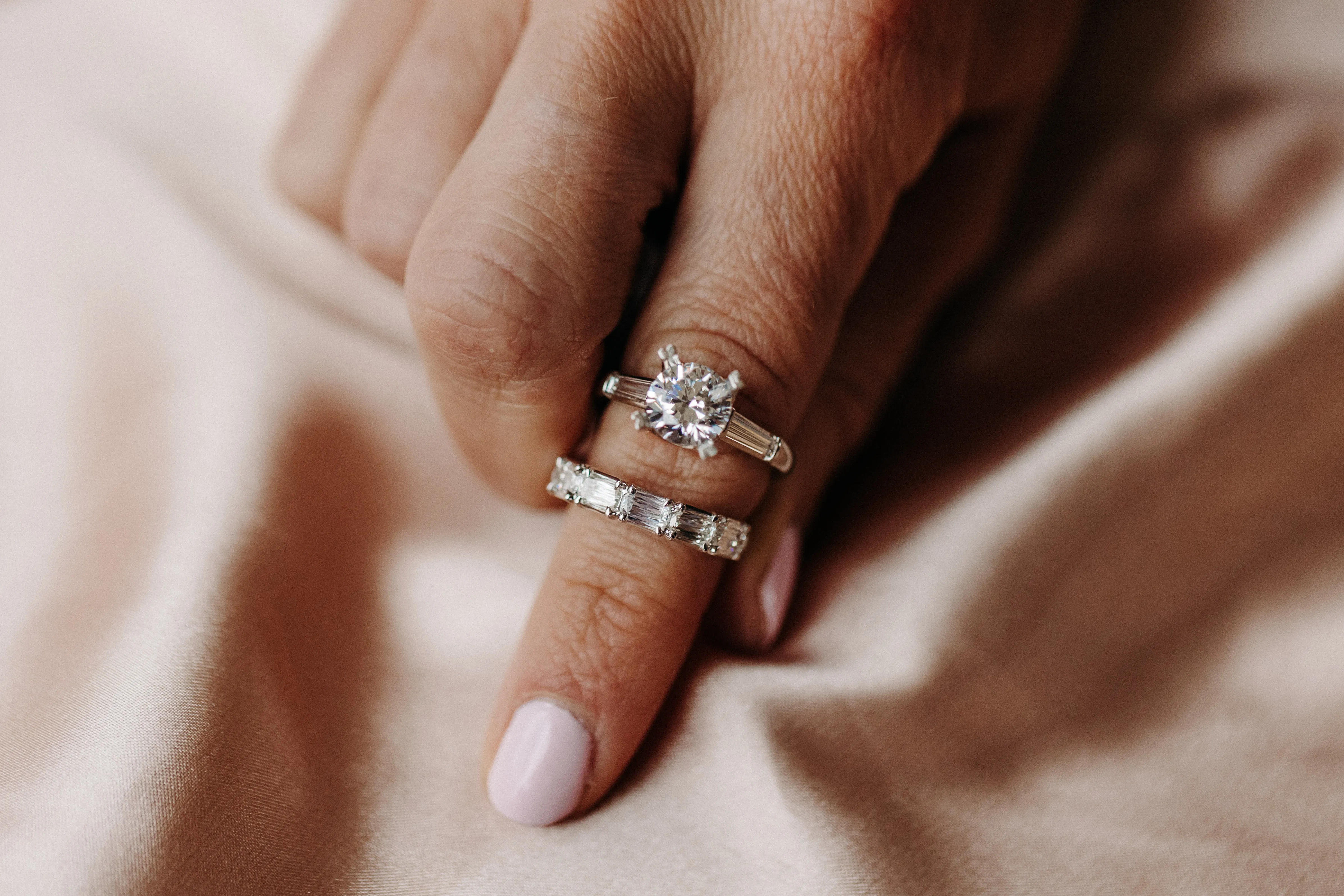 Elegant diamond engagement ring set on a hand, surrounded by greenery.
