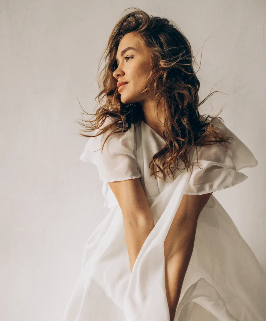 A hand holding a stunning diamond engagement ring with smaller diamonds on the band, set against a floral background.