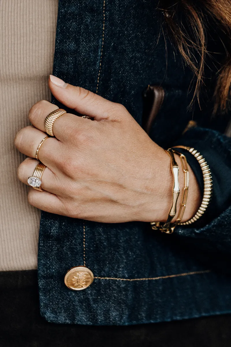Close-up of a hand adorned with multiple gold rings and bracelets, showcasing fine jewelry from Koerbers Fine Jewelry Inc.