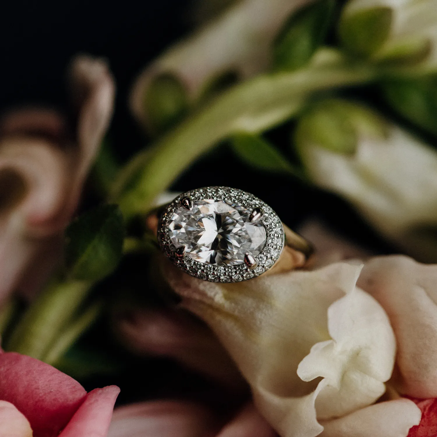 An elegant oval diamond engagement ring and a matching band displayed in a red velvet ring box.
