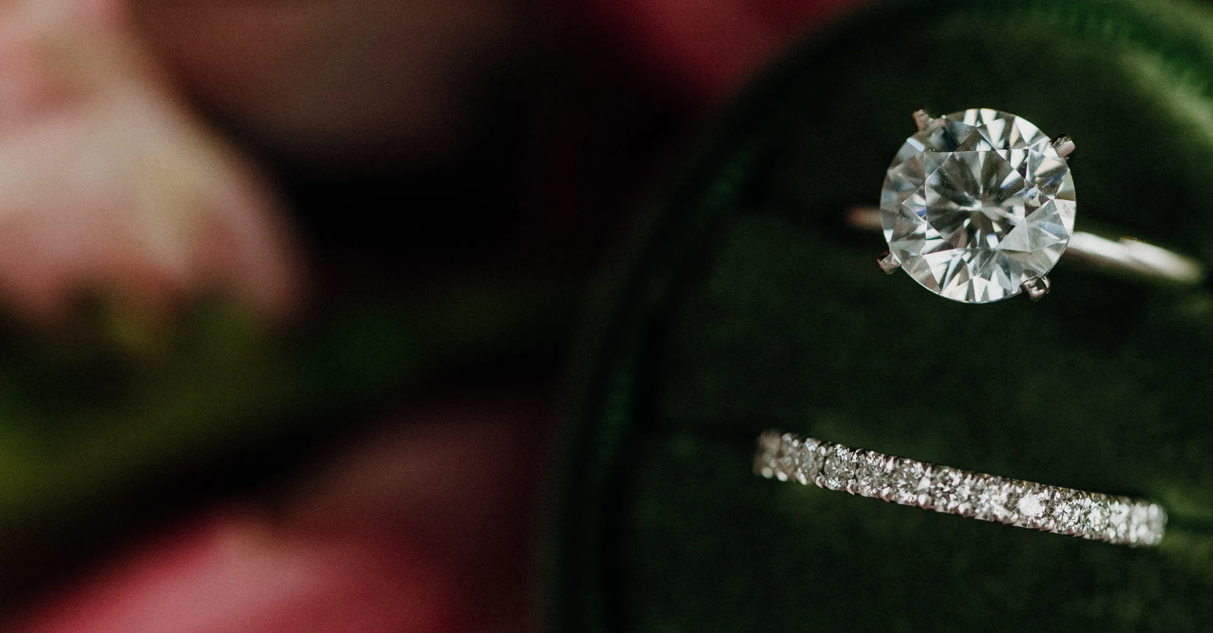 Engagement ring and wedding band displayed on a green velvet cushion.