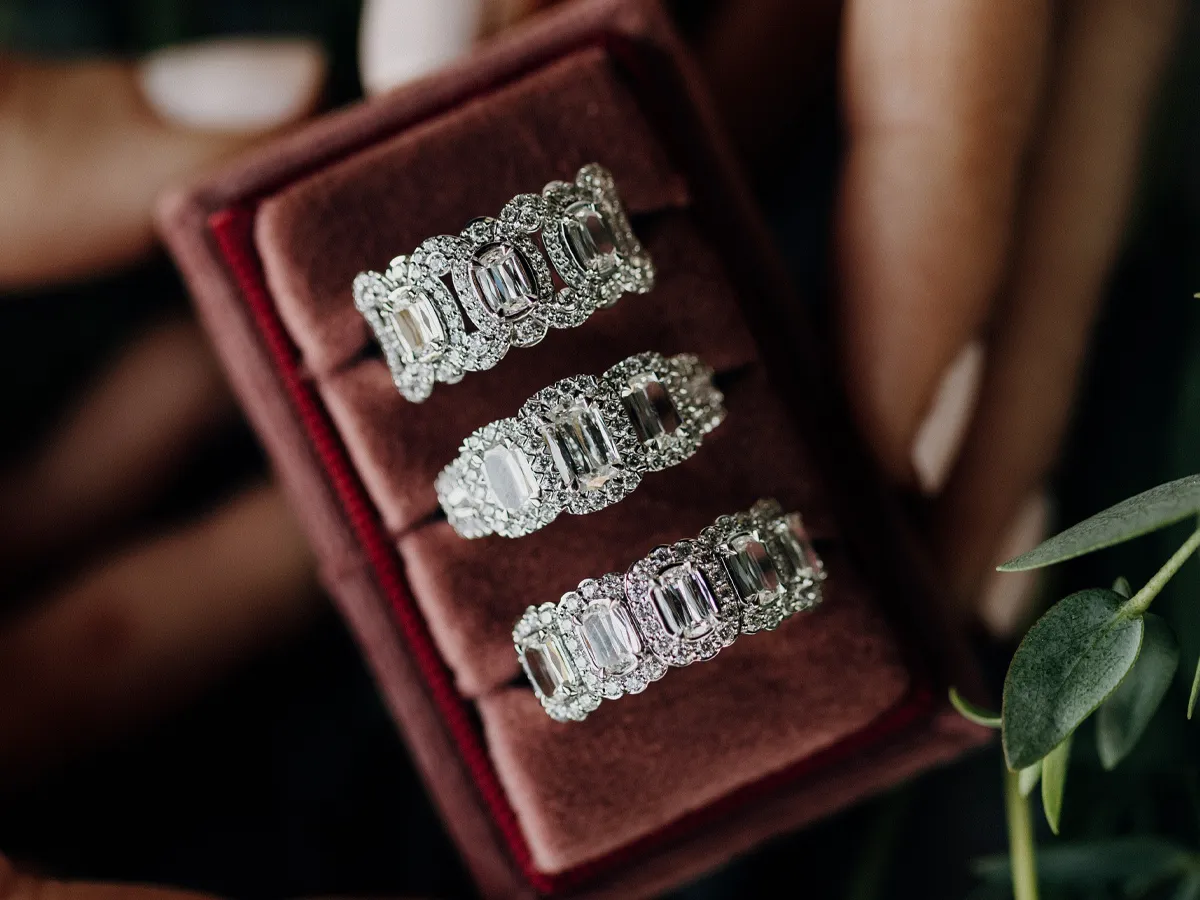 Three elegant silver wedding bands displayed in a red velvet box.