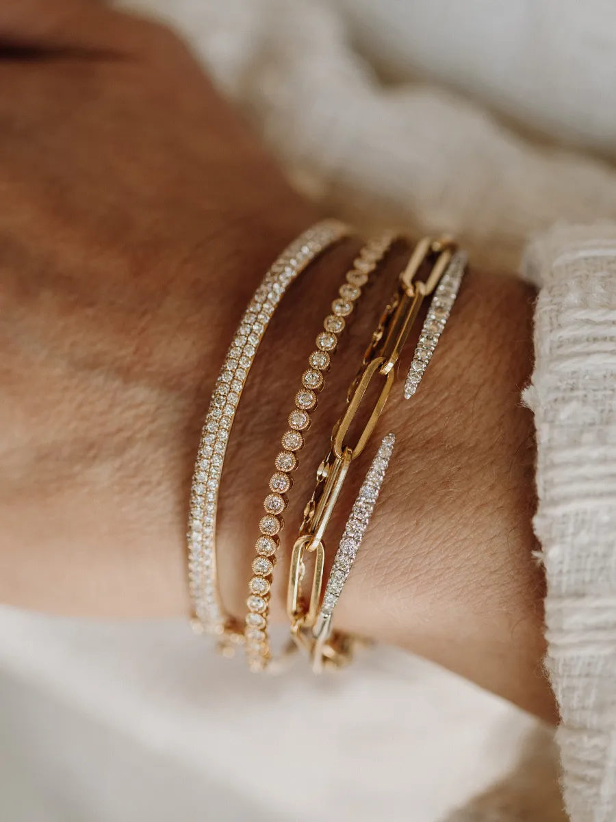 Elegant gold bracelets with sparkling stones, showcasing a stylish wrist accessory.