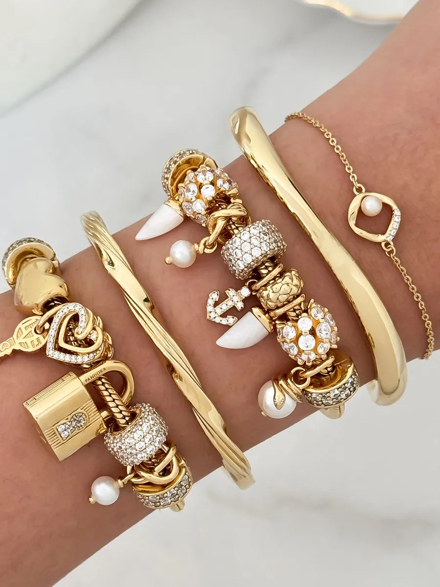 Gold and diamond charm bracelets stacked on a wrist.