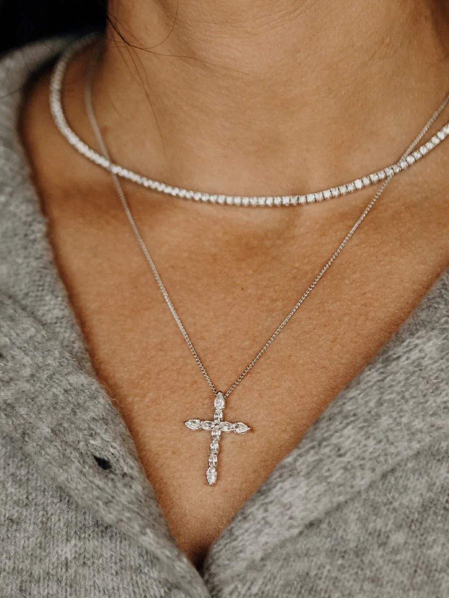 Close-up of a woman wearing a diamond cross necklace and a sparkling choker, showcasing fine jewelry from Koerbers Fine Jewelry.