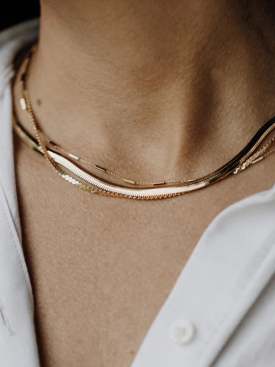 Close-up of layered gold necklaces worn on a neck, showcasing elegant jewelry.