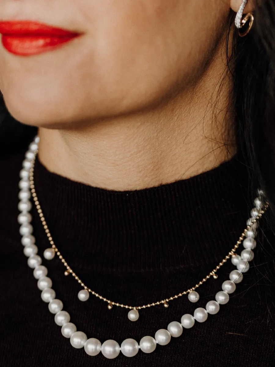 Close-up of a woman wearing layered pearl necklaces and red lipstick.