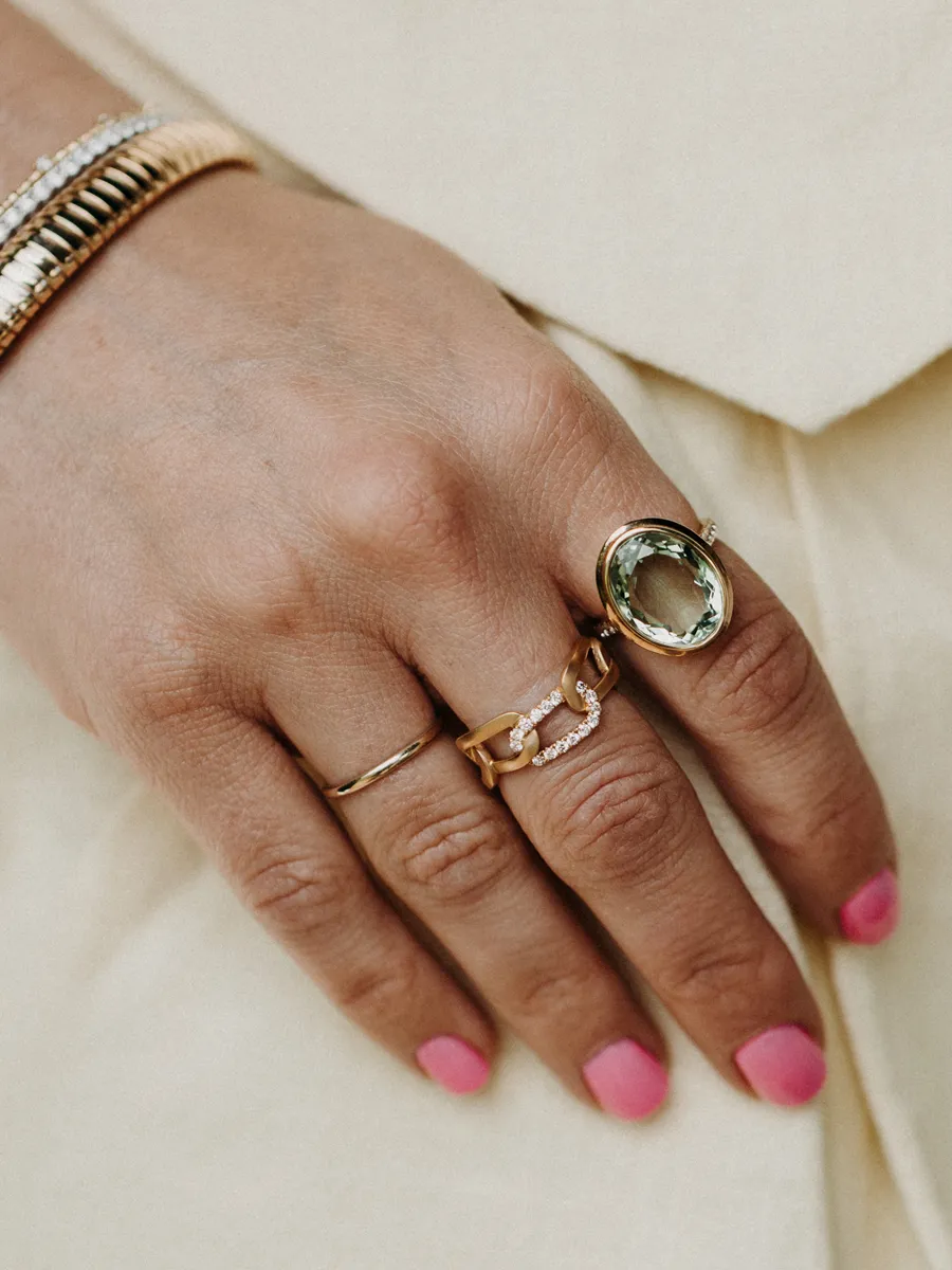 Stylish hand showcasing multiple rings, including a large green stone ring, perfect for fashion enthusiasts.