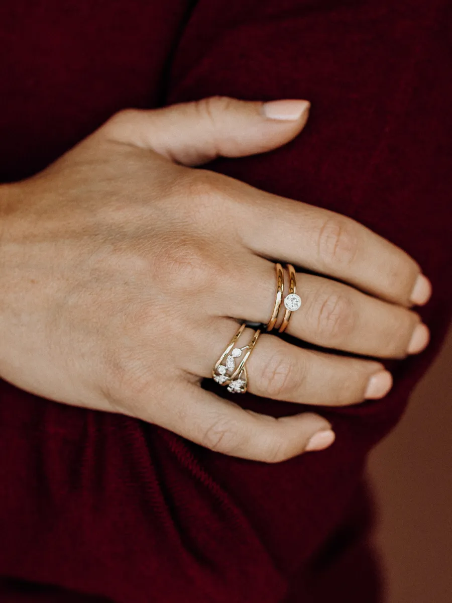 Close-up of a hand wearing stackable rings, featuring gold bands and a diamond ring.